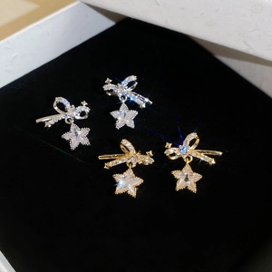 Detailed close-up of zircon bow and star earrings displayed in a luxury black velvet box