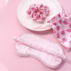 Pink silk sleep set with strawberry patterns including eye mask, scrunchie and pouch