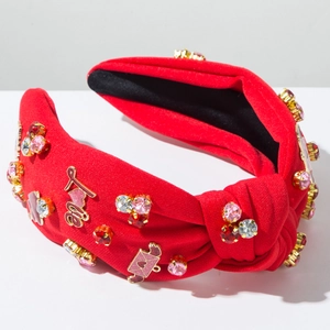 Dettaglio del cerchietto rosso annodato con cuori di cristallo e decori dorati Love