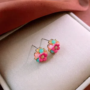 Exquisite floral beaded earrings with pink petals and gold pistils on beige velvet