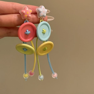 Detail of colorful Y2K earrings with star, large buttons and fringe beads on gold hook