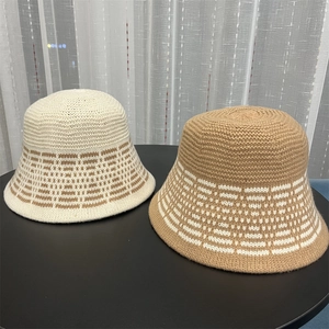 Close-up of beige and camel knitted bucket hats with geometric stripe patterns on a desk