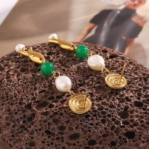 Detail of 18K gold-plated fish earrings with white pearls and green beads on a rock