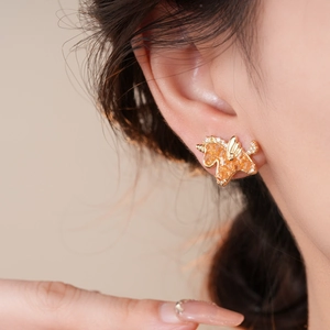 Golden unicorn stud earrings with orange rhinestones and sparkling crystals on model