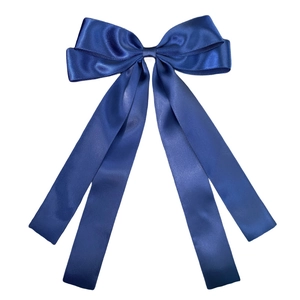 Detail of a dark blue satin double bow hair clip with elegant flowing ribbon texture