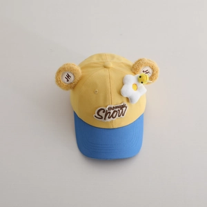 Gros plan d'un chapeau enfant jaune et bleu avec oreilles en peluche et décor fleur