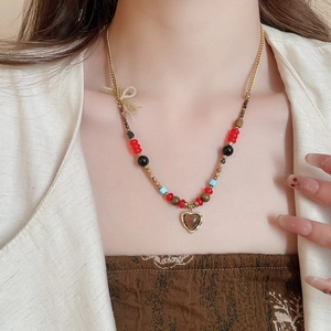 Detailed shot of tiger eye heart pendant with colorful beads on a gold chain necklace