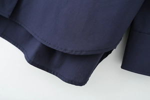 Macro detail of curved hem and stitching on navy blue cotton poplin long sleeve shirt
