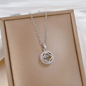 Close-up of a silver four-leaf clover pendant necklace with sparkling clear crystals