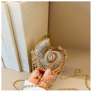 Detailed view of a gold shell-shaped mini metal clutch bag with a pearl chain strap