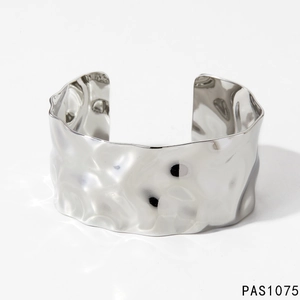 Detail of silver cuff bracelet showing irregular hammered texture and metallic mirror finish
