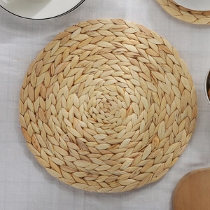 Handwoven round water hyacinth placemat with natural straw texture for dining table decor