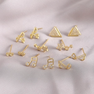 Elegant gold geometric stud earrings with sparkling zircon on silk background