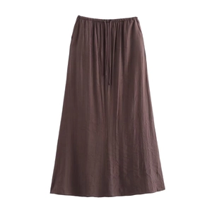 Détail d'une jupe plissée marron foncé avec taille réglable par cordon et texture fine