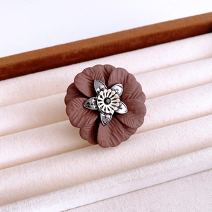Macro detail of a flower-shaped ring with brown matte petals and dark gem center