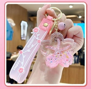 Macro shot of pink flower shaped acrylic liquid keychain with floating glitter and starfish