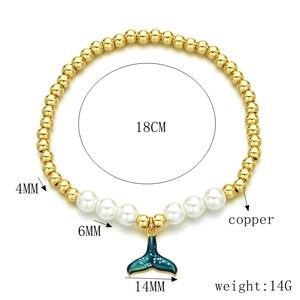 Detail of gold beaded bracelet with pearl accents and teal fish tail charm