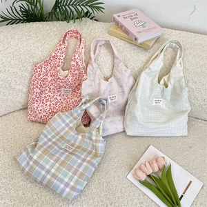 Close-up of assorted plaid and leopard print canvas tote bags on a cozy white rug