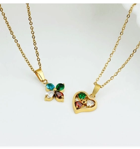 Detailed macro view of gold-plated necklaces with cross and heart-shaped colorful zircons