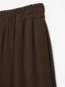Detail of elastic waistband and dark brown textured fabric on fashionable casual trousers