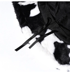 Close-up of plush cow print fabric texture and black ribbon detail on a winter bucket hat