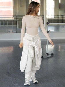 Full view of women's ribbed long sleeve tee and beige joggers in a minimalist studio