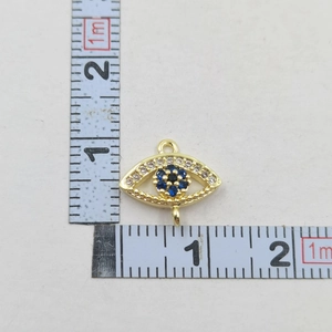 Detail view of the evil eye pendant size dimensions on a scale showing 1.5cm by 2cm width