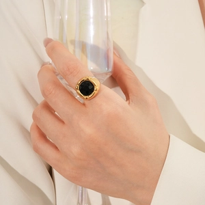 Dettaglio di un anello vintage con gemma nera quadrata e montatura dorata sulla mano