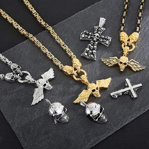 Gothic skull cross necklaces with wings in gold and silver finish on stone background