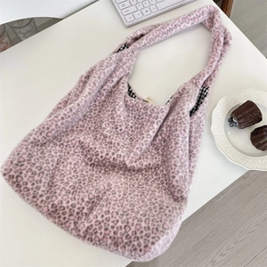 Detailed view of pink leopard print plush hobo bag with plaid lining on a white desk