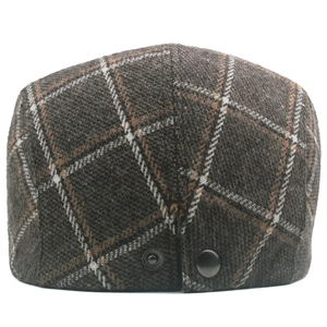 Detail of vintage brown plaid wool flat cap showing textured fabric and back metal button