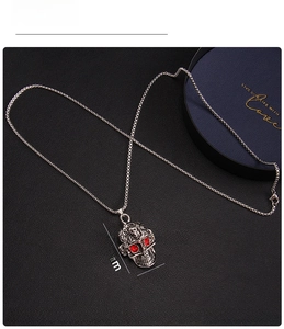 Gros plan d'un pendentif crâne punk avec yeux en strass rouges et métal argenté ciselé