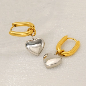 Gold U-shaped hoop earrings with silver heart pendants on elegant fabric background
