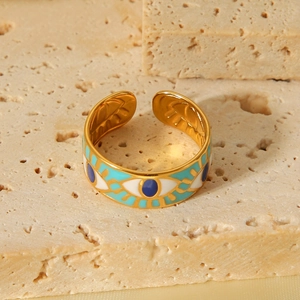 Detail of gold evil eye open ring with blue and turquoise enamel on travertine stone