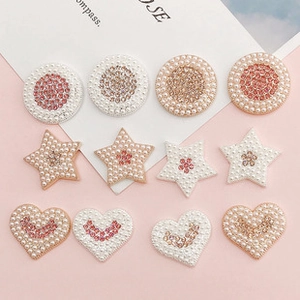 Detailed view of DIY heart and star charms with pearls and pink rhinestones