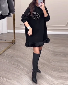 Détail de robe sweat noire à manches longues avec art floral blanc et ourlet à volants