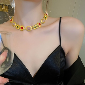 Detail of vintage gold necklace with embossed portrait charms and red heart accents