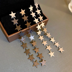 Golden star tassel drop earrings with matte metallic finish on a jewelry box