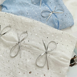 Detailed view of sequins and 3D bows on white and blue tulle fabric for handbag