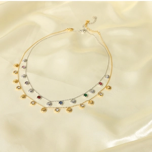Detail of 18k gold and silver necklaces with colorful zircons and shell pendants on satin