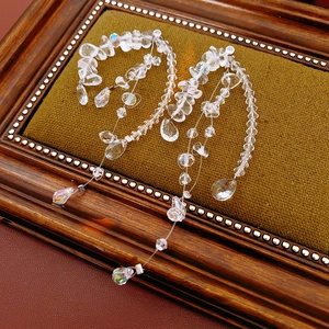 Macro detail of long crystal tassel earrings on vintage green velvet display