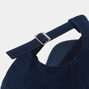 Detail of adjustable silver metal buckle on navy blue baseball cap for custom fit