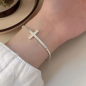 Detailed view of a silver cross pendant on a sleek 2mm box chain bracelet worn on wrist