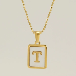 Macro view of gold-plated necklace featuring a white square pendant with capital letter T