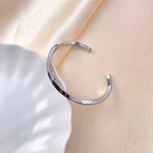 Bracciale rigido aperto Mobius in argento lucido esposto su un vassoio a conchiglia