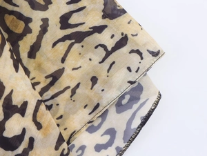 Close-up of leopard print chiffon fabric with delicate black stitching on the hem