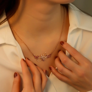Close-up of rose gold name necklace with Alice script and pink crystal butterfly details