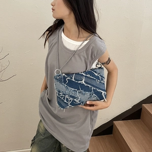 Chic blue denim crossbody bag with fringe details and chain strap worn by a model