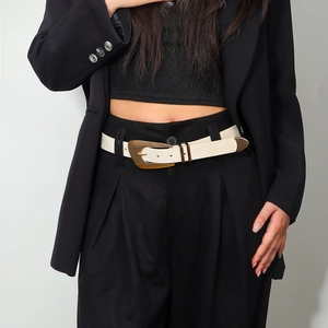 Close-up of a white woven belt with a large irregular gold metal buckle on a black blazer