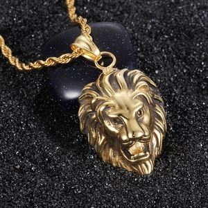 Macro shot of gold lion head pendant with textured twist chain on black surface